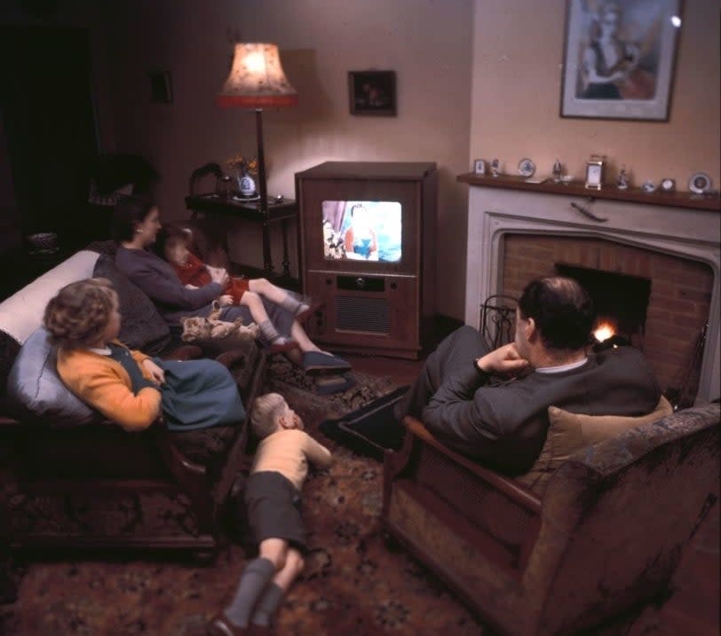 Family of four watching television in a vintage living room setting
