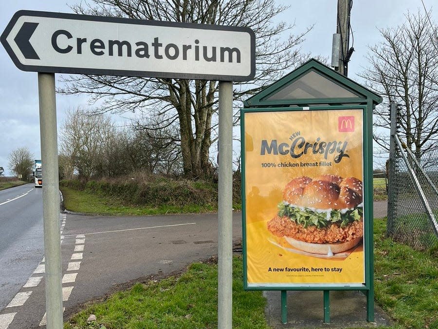 A McDonald's advert at a bus stop next to a sign for a crematorium