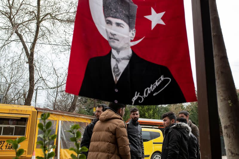 Migrants stand on a street by the Turkish flag with a portrait of modern Turkey's founder Mustafa Kemal Ataturk in Karaagac district near Turkey's Pazarkule border crossing with Greece's Kastanies, in Edirne