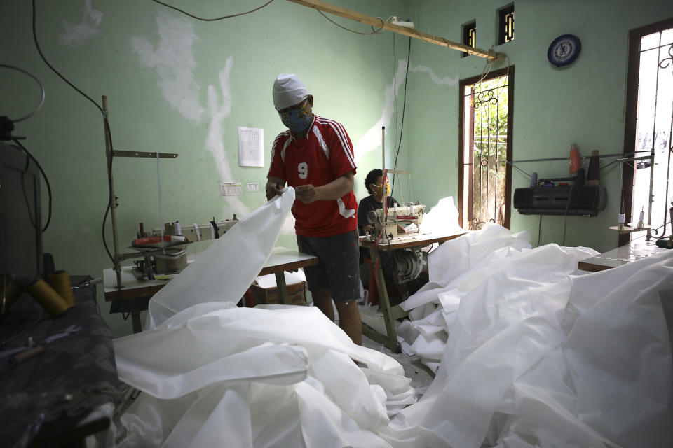 In this Thursday, April 2, 2020, photo, tailors make hazmat suits at a home garment factory in Depok, Indonesia. When an Indonesian businesswoman Maryati Dimursi heard from friends working in hospitals that they don't have enough proper protective gear when dealing with suspected COVID-19 patients, she decided to help them by crowdfunding to produce proper hazmat suits for distribution to various hospitals in the country. (AP Photo/Dita Alangkara)