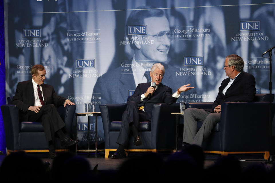 Former President Bill Clinton, center, speaks to former Florida Gov. Jeb Bush, right, during a discussion at a George and Barbara Bush Distinguished Lecture, Friday, Sept. 27, 2019, at the University of New England n Biddeford, Maine. The discussion was moderated by Harvard University professor Roger Porter, left. (AP Photo/Robert F. Bukaty)