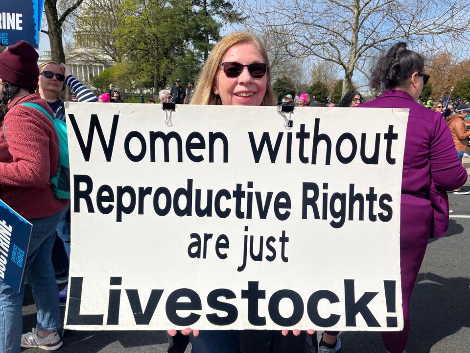A demonstrator holds a sign that reads, “Women without Reproductive Rights are just Livestock!