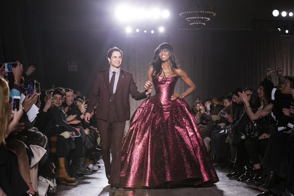 FILE - In this Feb. 16, 2015, file photo, designer Zac Posen and model Naomi Campbell greet the crowd after his Fall 2015 collection is modeled during Fashion Week, in New York. Posen is shutting down his namesake label. Posen, 39, said he was “deeply saddened that the journey of nearly 20 years has come to an end.” He launched his label in 2001. (AP Photo/John Minchillo, File)