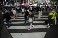 People walk along a pedestrian crossing Friday, July 30, 2021, in Tokyo, as Japanese Prime Minister Yoshihide Suga expanded a coronavirus state of emergency to four more areas in addition to Tokyo following record spikes in infections as the capital hosts the Olympics. (AP Photo/Eugene Hoshiko)