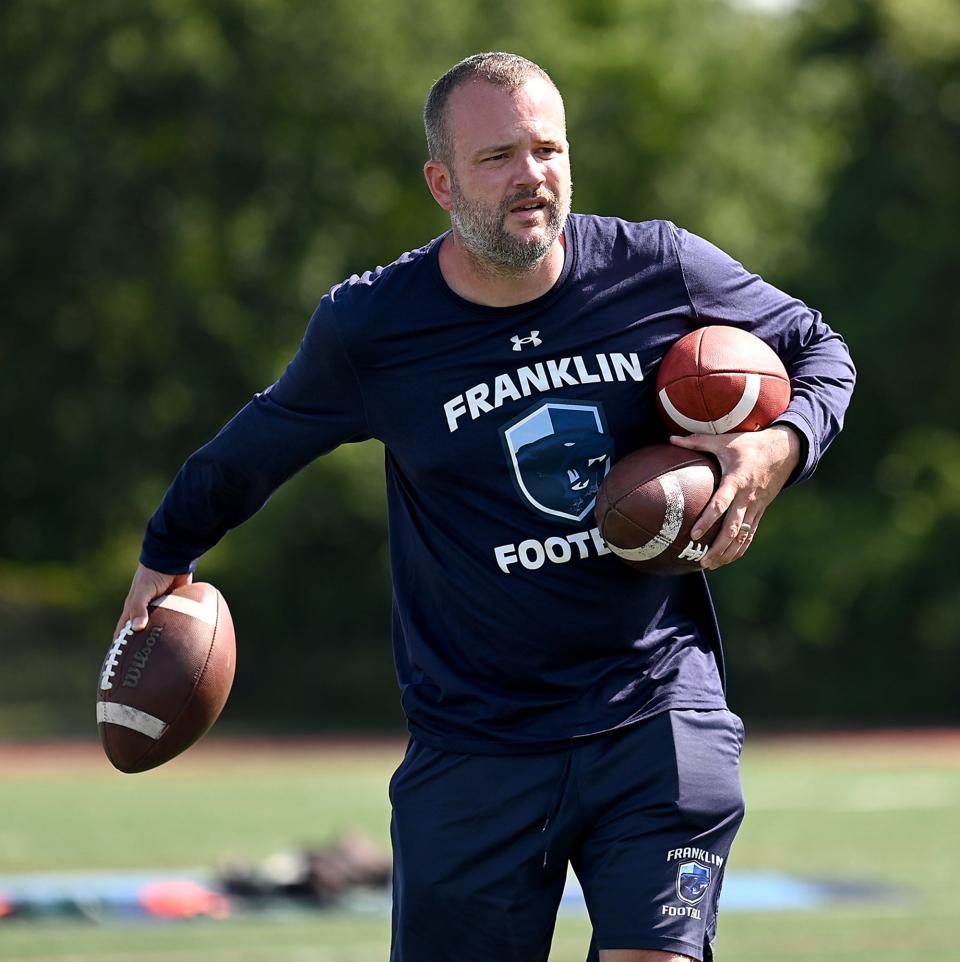 Franklin football coach Eian Bain tosses footballs to players during the first day of practice at Franklin High School, Aug. 19, 2022.