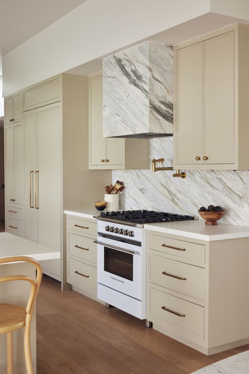 Marble backsplash and hood vent cover, white vintage inspired oven, tan cabinets