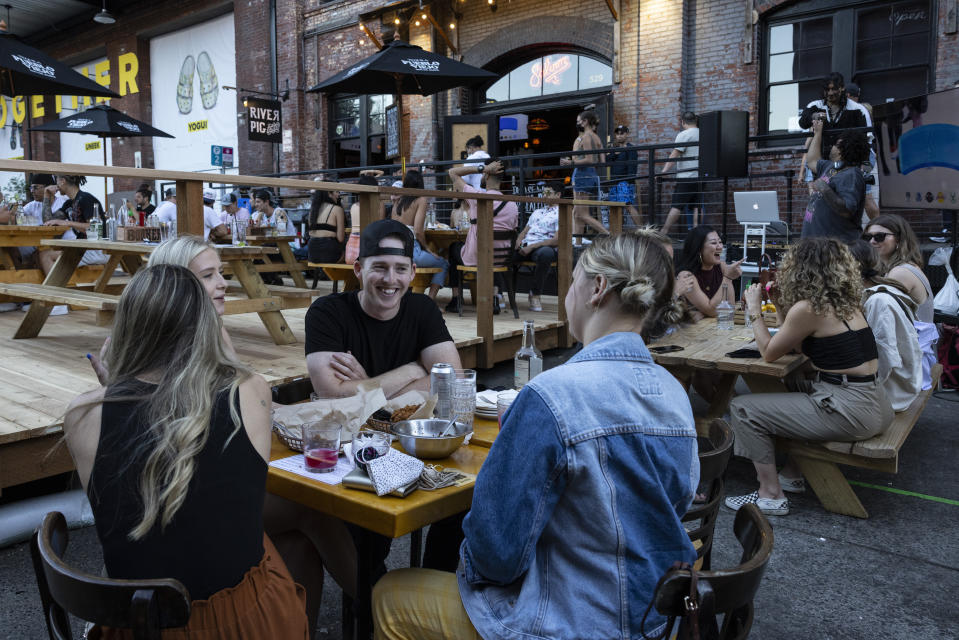 People enjoy dinner and drinks unmasked at the River Pig restaurant in Portland, Ore., on Friday, June 4, 2021. Until a year ago, the city was best known nationally for its ambrosial food scene, craft breweries and “Portlandia” hipsters. Now, months-long protests following the killing of George Floyd, a surge in deadly gun violence, and an increasingly visible homeless population have many questioning whether Oregon’s largest city can recover. (AP Photo/Paula Bronstein)