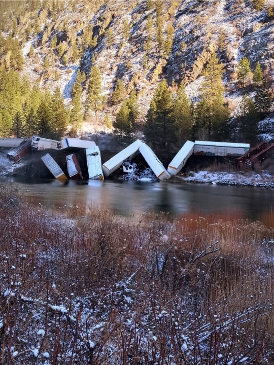 This image provided by Daffney Clairmont shows a train derailed along the Clark Fork River near Paradise, Mont., Sunday, April 2, 2023. Authorities say about 25 train cars derailed. (Daffney Clairmont via AP)