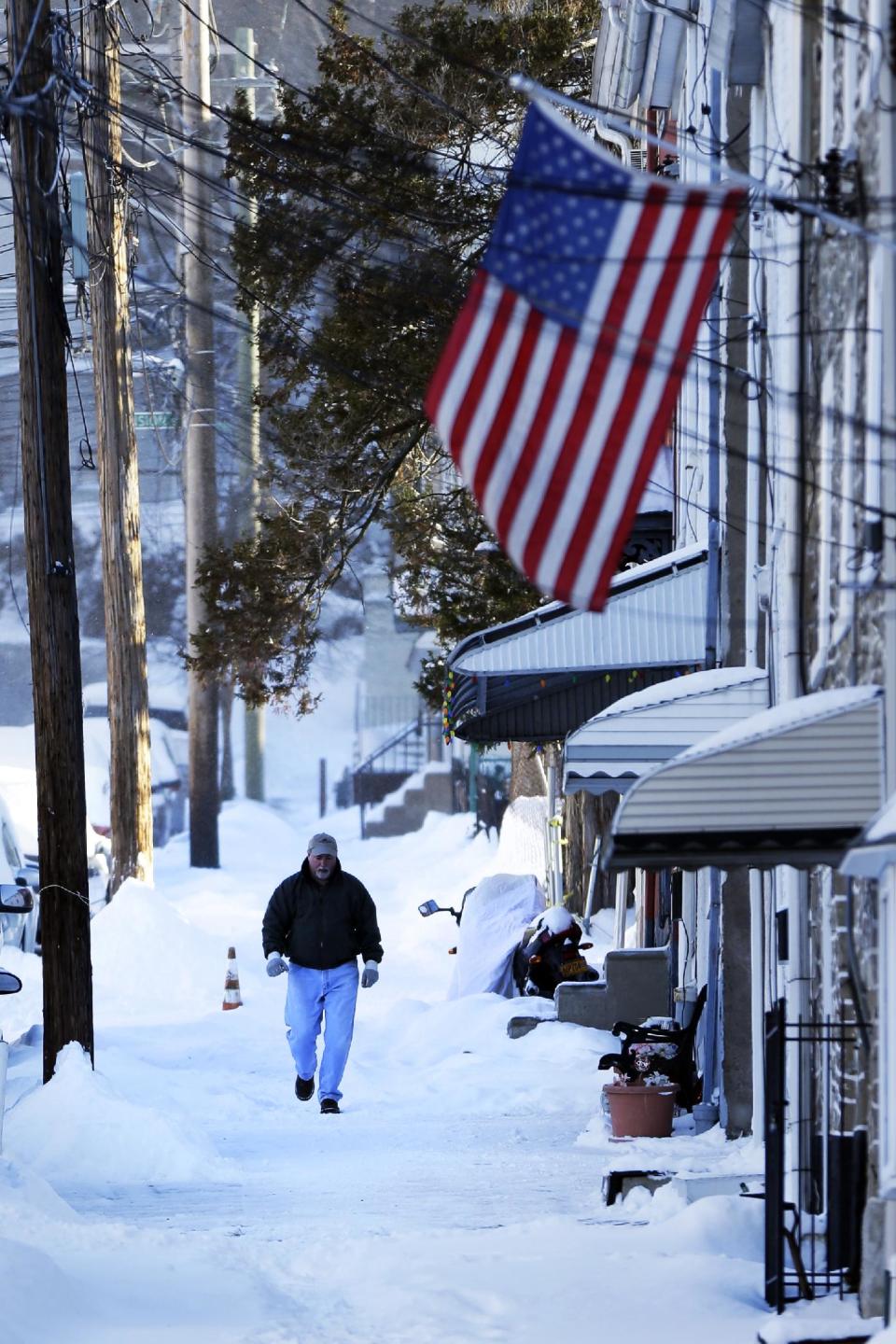 A man walks on an un-shoveled sidewalk in the aftermath of a snowstorm Wednesday, Jan. 22, 2014, in Philadelphia. A winter storm stretched from Kentucky to New England and hit hardest along the heavily populated Interstate 95 corridor between Philadelphia and Boston. (AP Photo/Matt Rourke)