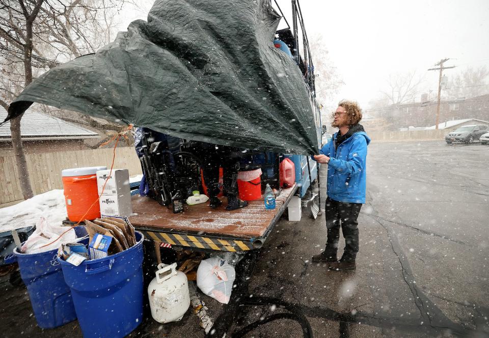 Volunteer Taylor Burke tries to secure a tarp during a windy snow storm so that an unsheltered female will be able to have some privacy in the designated bathroom area on the back of the Nomad Alliance bus.