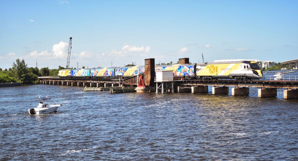 A boat floats in between the Old Roosevelt Bridge and a railroad drawbridge in Stuart waiting for a Brightline train to cross the St. Lucie River on Sept. 22, 2023, the first day of passenger service between Miami and Orlando.