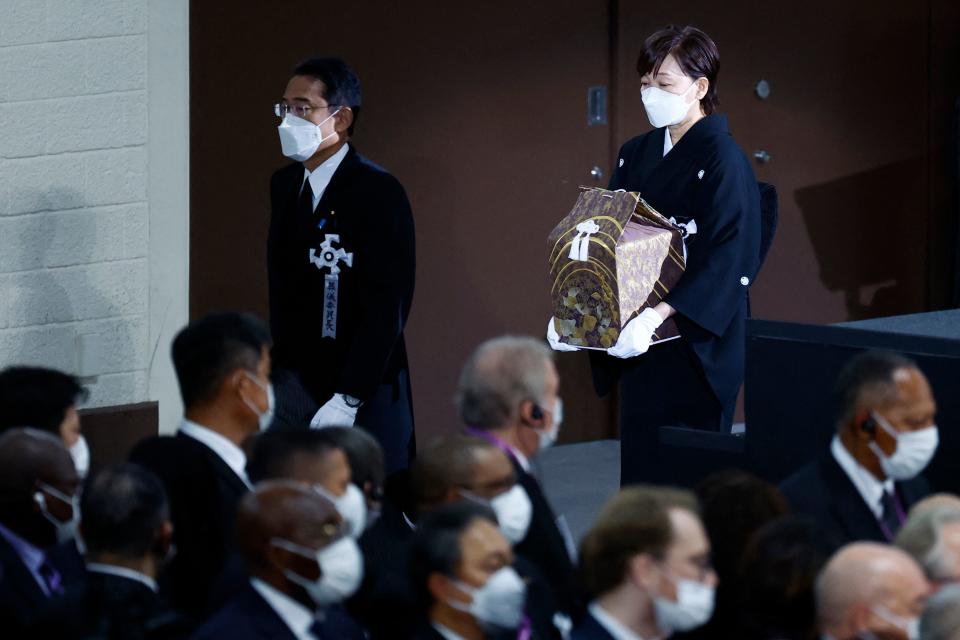 安倍昭惠捧著亡夫骨灰，隨著日本首相岸田文雄走入國葬會場。（AFP）