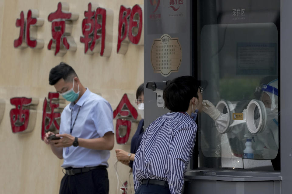 A worker gets a throat swab at a COVID-19 testing facility in Beijing, Monday, June 13, 2022. China's capital has put school online in one of its major districts amid a new COVID-19 outbreak linked to a nightclub, while life has yet to return to normal in Shanghai despite the lifting of a more than two month-long lockdown. (AP Photo/Andy Wong)