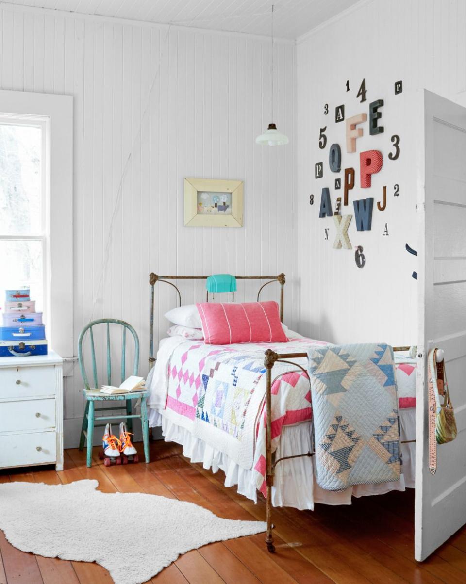 a light filled room decorated with handsome hand me downs and the bed previously belonged to her great uncle and the quilts have been passed down by various family members and the stack of suitcases are from family