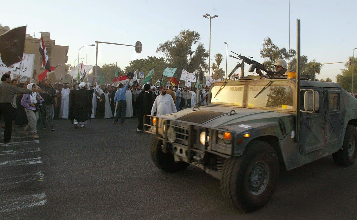 US soldiers drive past Shia Muslims from the working class neighborhood of Sadr City protesting on 25 August, 2003 (AFP/Getty)