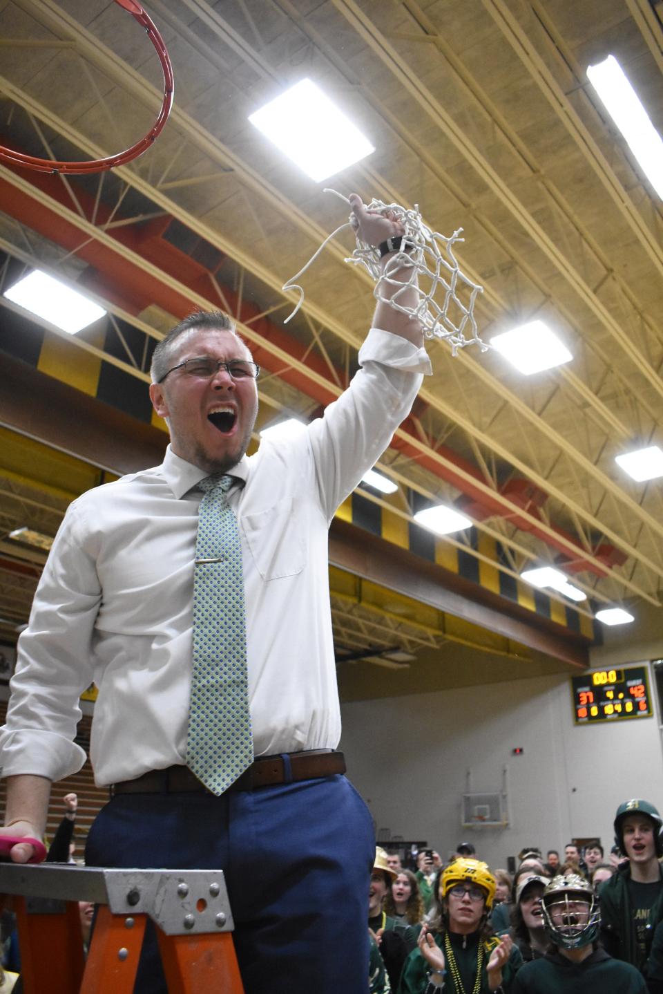 Howell coach Nick Simon celebrates after cutting down the net following a 42-37 victory over Oxford in the regional basketball championship game on Thursday, March 7, 2019.