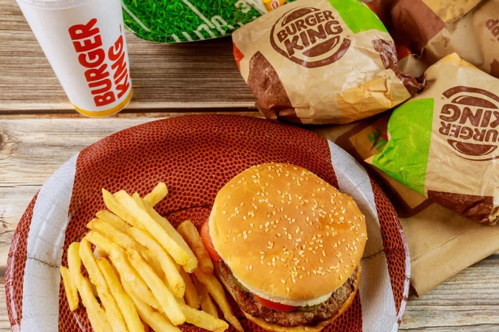 A burger sits on a plate with fries and other burgers around it. 