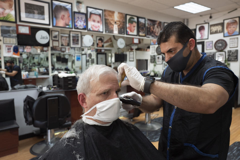 Howard Kaplan gets a haircut from Eli Gilkarov at Jack's Barbershop, Tuesday, June 9, 2020, in Larchmont, N.Y. Counties north of New York City are reopening businesses as part of Phase 2 during the coronavirus pandemic. The barbershop is doing haircuts by appointment with limited numbers of customers in the store at any time. (AP Photo/Mark Lennihan)