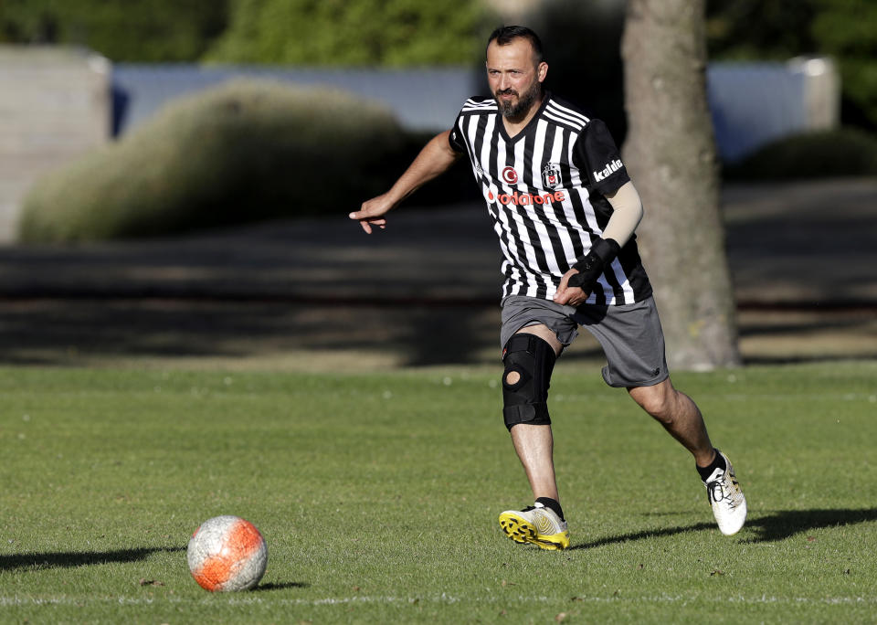 In this Wednesday, Feb. 26, 2020, photo, Al Noor mosque shooting survivor Temel Atacocugu chases the ball during a social game of soccer in Christchurch, New Zealand. When the gunman walked into the mosque, Atacocugu was kneeling for Friday prayers. He looked up into the man's face, thinking he was a police officer because of his paramilitary outfit. Time slowed. Temel saw a puff of smoke come from the raised gun, felt a bullet smash into his teeth, and thought: "Oh, my God, I'm dying." (AP Photo/Mark Baker)