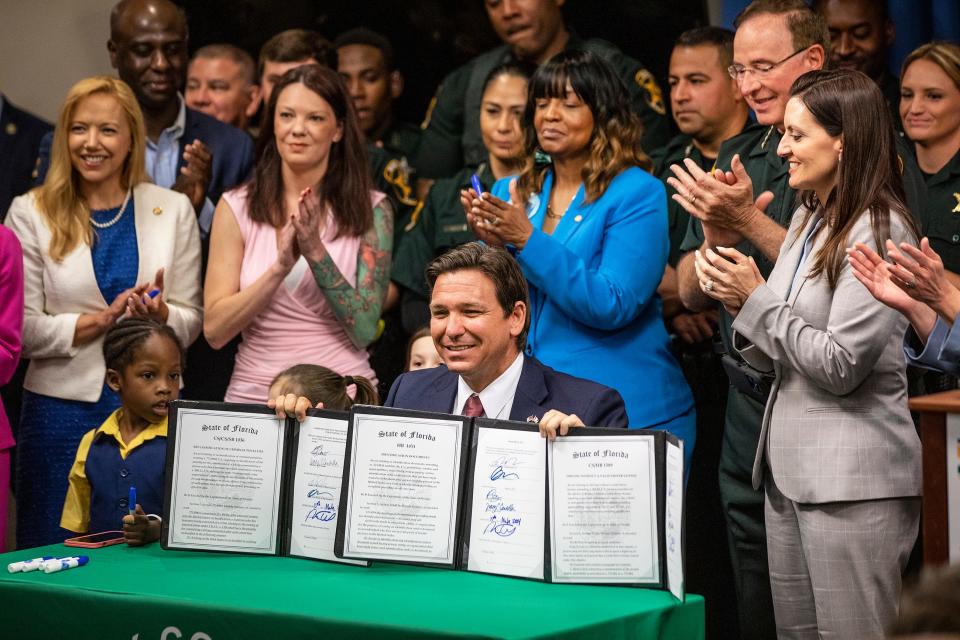 Gov. Ron DeSantis holds three pieces of legislation he signed on immigration during a press conference held in Winter Haven on March 15, 2024.