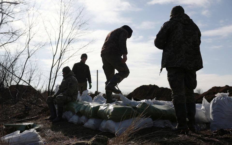 Ukrainian servicemen pile up earthbags to build a fortification not far from town of Avdiivka