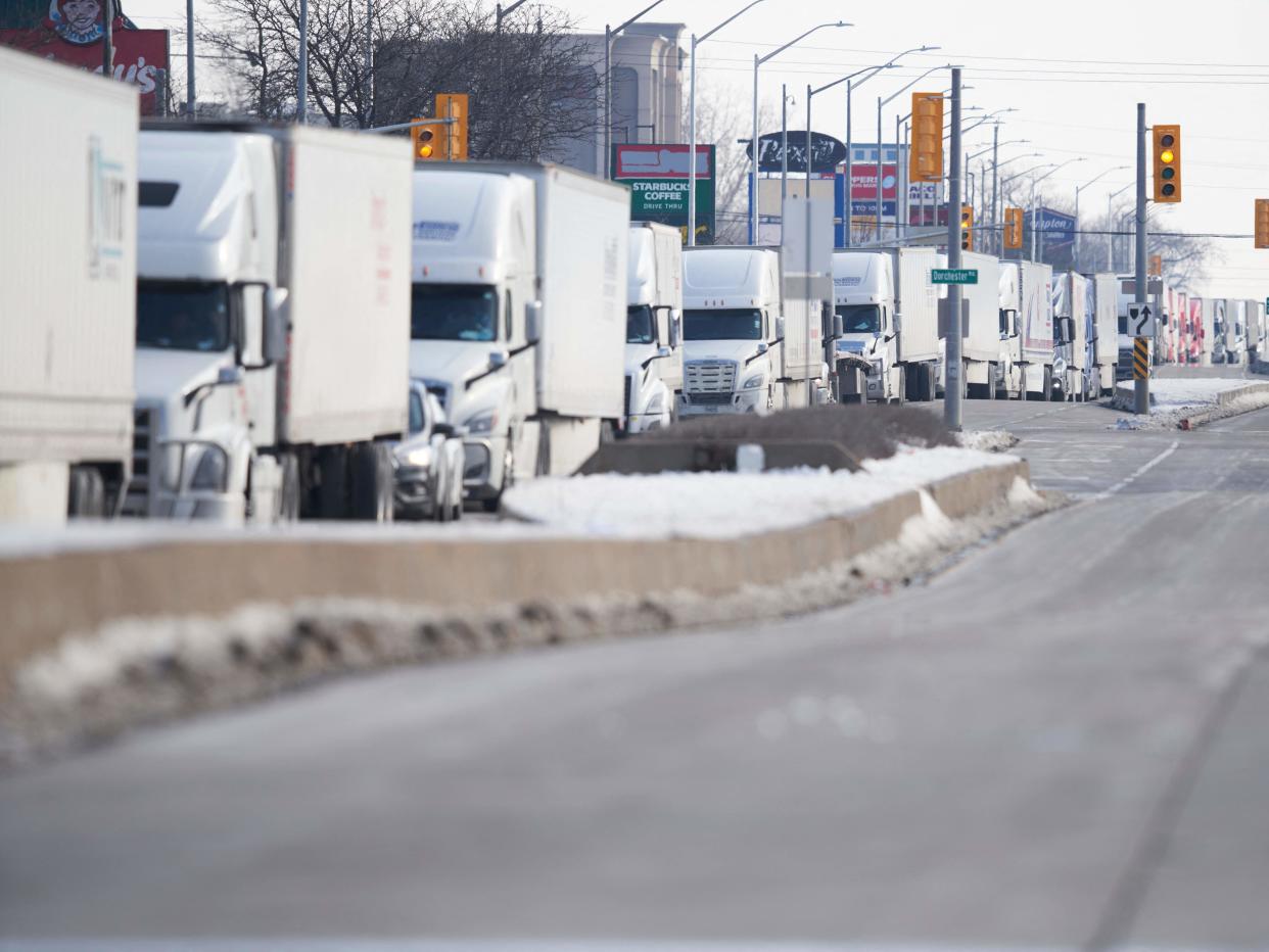 A line of trucks waits for the road to the Ambassador Bridge border crossing in Windsor, Ontario to reopen February 8, 2022, after protesters blocked the road Monday night.