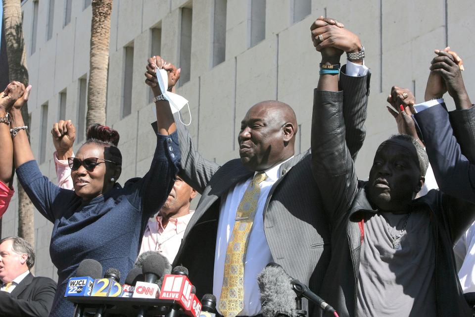 Attorney Benjamin Crump holds up the arms of Ahmaud Arbery's parents, Wanda Cooper-Jones and Marcus Arbery Tuesday, Feb. 22, 2022 outside the federal courthouse in Brunswick, Ga.