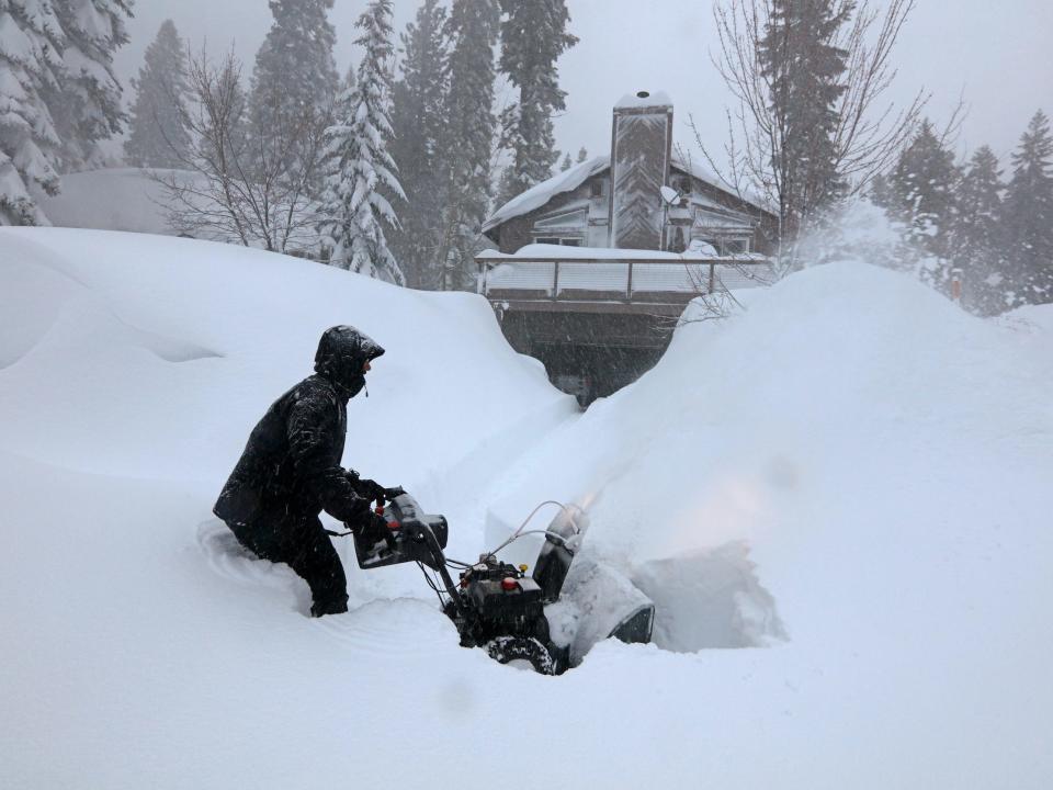 A man clears snow from driveway using snow-blower near Lake Tahoe