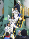 In this photo released by the Roscosmos Space Agency, Roscosmos cosmonaut Alexander Misurkin, bottom, and spaceflight participants Yusaku Maezawa, center, and Yozo Hirano, above, of Japan, members of the main crew of the new Soyuz mission to the International Space Station (ISS) wave as they board to the spaceship prior the launch at the Russian leased Baikonur cosmodrome, Kazakhstan, Wednesday, Dec. 8, 2021. (Pavel Kassin, Roscosmos Space Agency via AP)