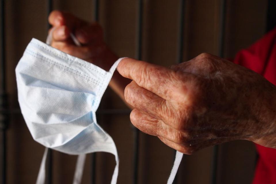 Manos de anciana sosteniendo una mascarilla