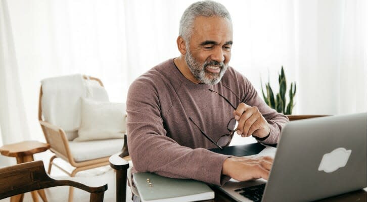 一位退休人员在他的电脑上查看他的投资组合。 尽管存在熊市，但使用桶策略的模型投资组合已帮助退休人员在 2022 年保持现金流。