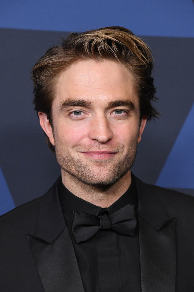 dressed in a monochromatic suit, Rob smirks on the red carpet