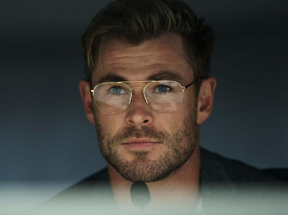 Chris Hemsworth in glasses with a microphone in front of him