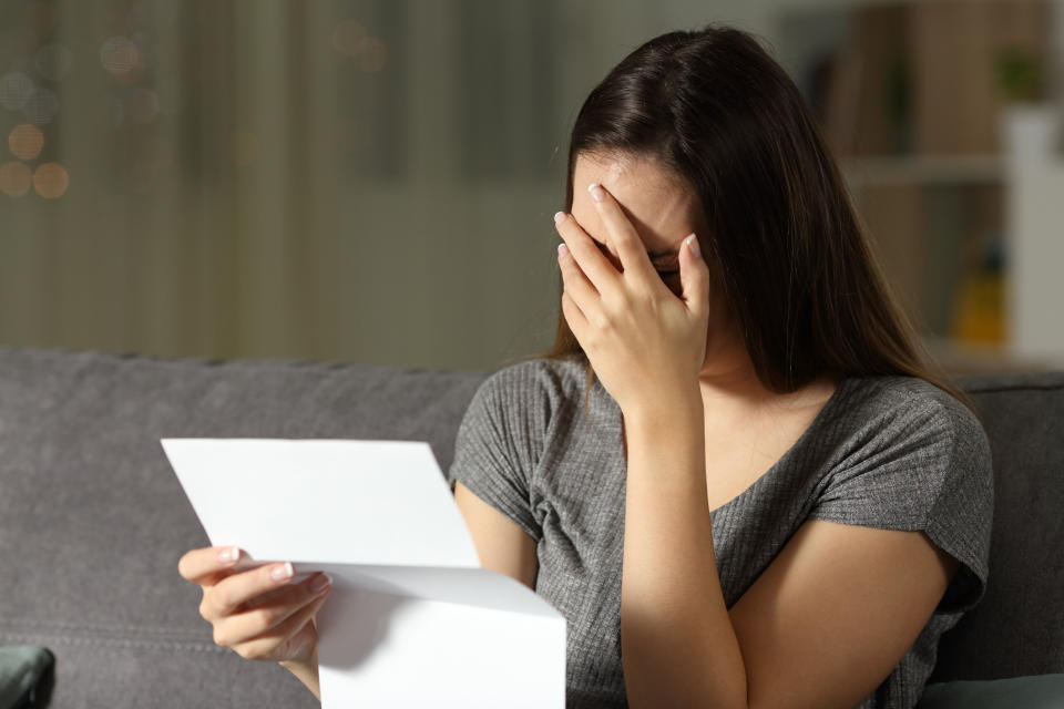 Woman covering her face while holding a document