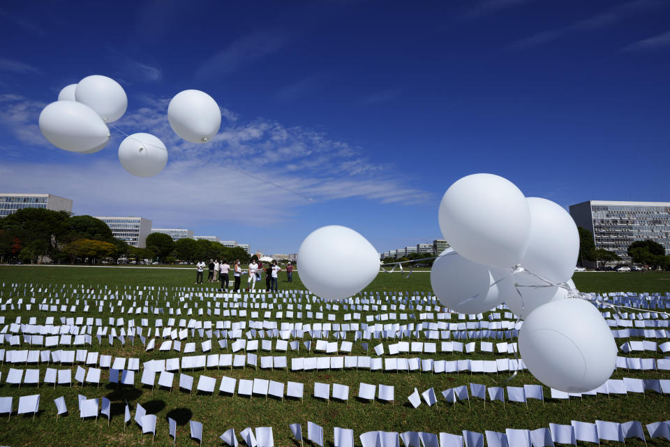 White flags representing people who have died of COVID-19 in Brazil cover a field as part of a protest against the government's health policies outside the National Congress in Brasilia, Brazil, Friday, Oct. 15, 2021. Activists said they placed 600 flags, each with a person's name, to represent the 600,000 death toll, announced the previous day. (AP Photo/Eraldo Peres)