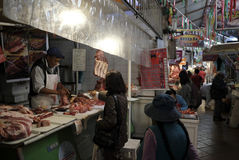A butcher attends to a customer at a market in La Paz, Bolivia, Friday, June 28, 2024, two days after Army troops stormed the government palace in what President Luis Arce called a coup attempt.(AP Photo/Carlos Sanchez)