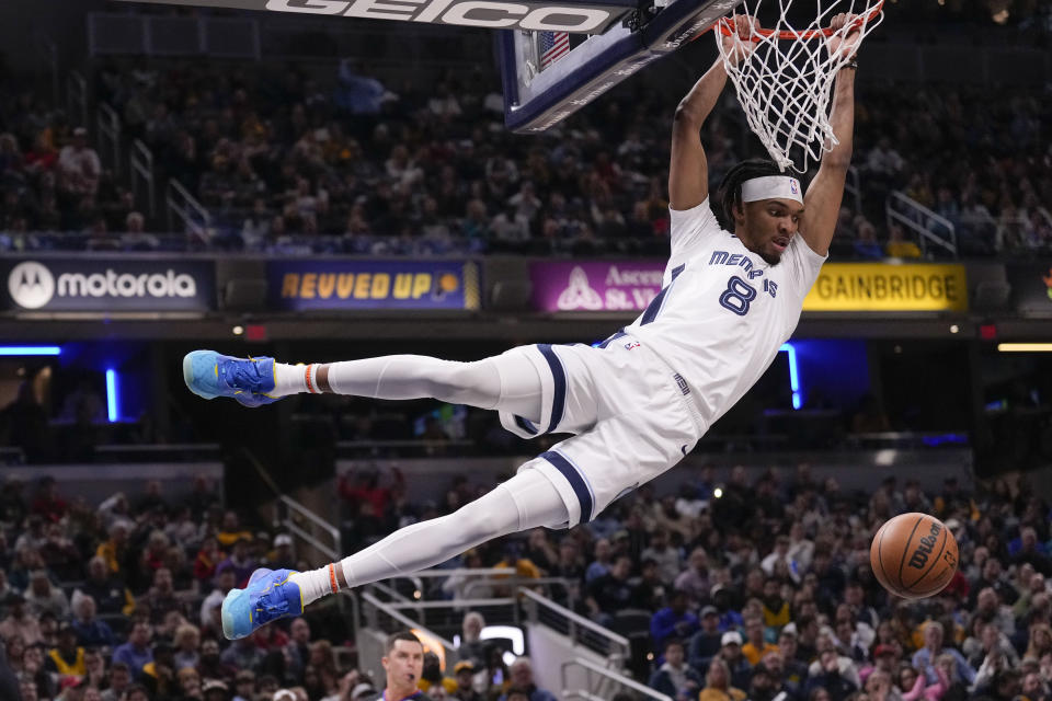 Memphis Grizzlies forward Ziaire Williams (8) hangs from the rim after dunking during the first half of an NBA basketball game against the Indiana Pacers in Indianapolis, Saturday, Jan. 14, 2023. (AP Photo/AJ Mast)