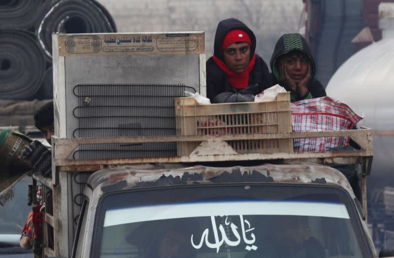 FILE PHOTO: Displaced Syrian boys ride on a truck with belongings in northern Idlib