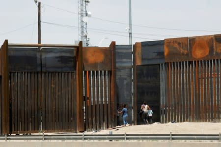 Migrants walk along the border fence after crossing illegally into El Paso, Texas, U.S., to request asylum, as seen from Ciudad Juarez