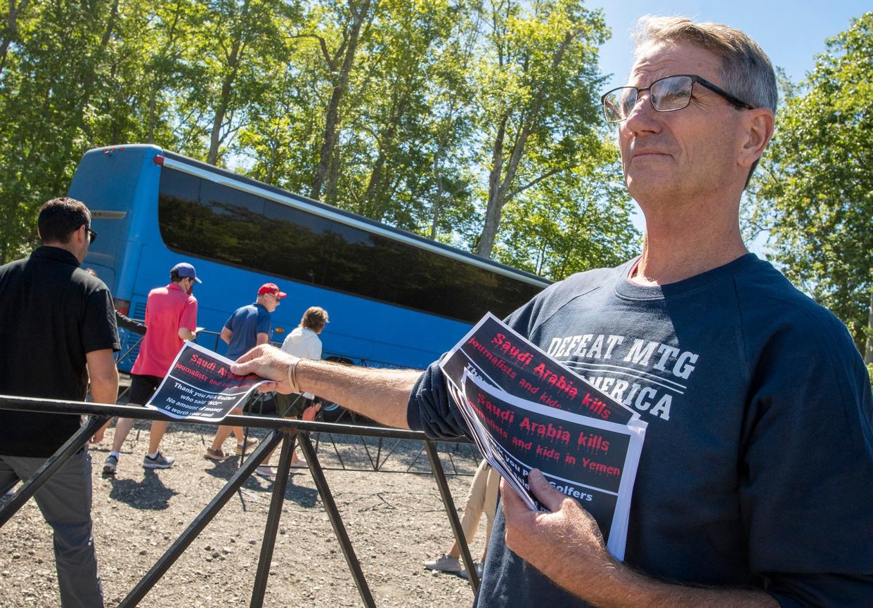 Kevin Moulton of Sterling hands flyers to people boarding shuttle buses in Lancaster on their way to attend the LIV Golf Invitational Boston, Friday, in Bolton.