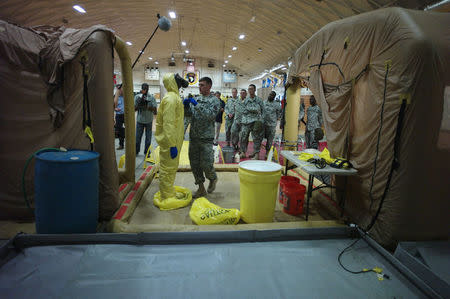 A U.S. Army soldier from the 101st Airborne Division (Air Assault), who are earmarked for the fight against Ebola, goes through decontamination process training before their deployment to West Africa, at Fort Campbell, Kentucky October 9, 2014. REUTERS/Harrison McClary