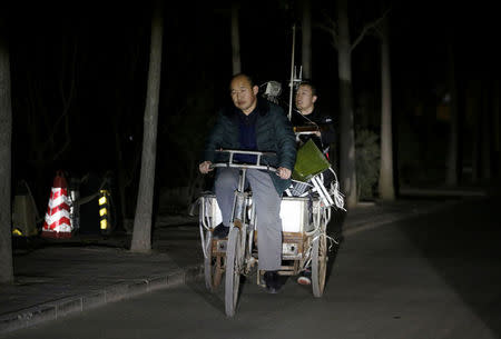 Migrant workers ride a tricycle filled with luggage as they are forced to move out of their apartments before midnight at a village outside the sixth ring road in Tongzhou district of Beijing, China, November 23, 2017. Picture taken November 23, 2017. REUTERS/Jason Lee