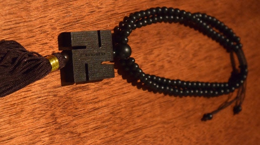 A set of prayer beads bearing the image of a swastika, among the religious possessions of  Buddhist priest T.K. Nakagaki, who came to the U.S. in 1986 from his native Japan. Despite its appropriation by Nazi Germany, the swastika remains a revered symbol among Dharmic faiths worldwide.