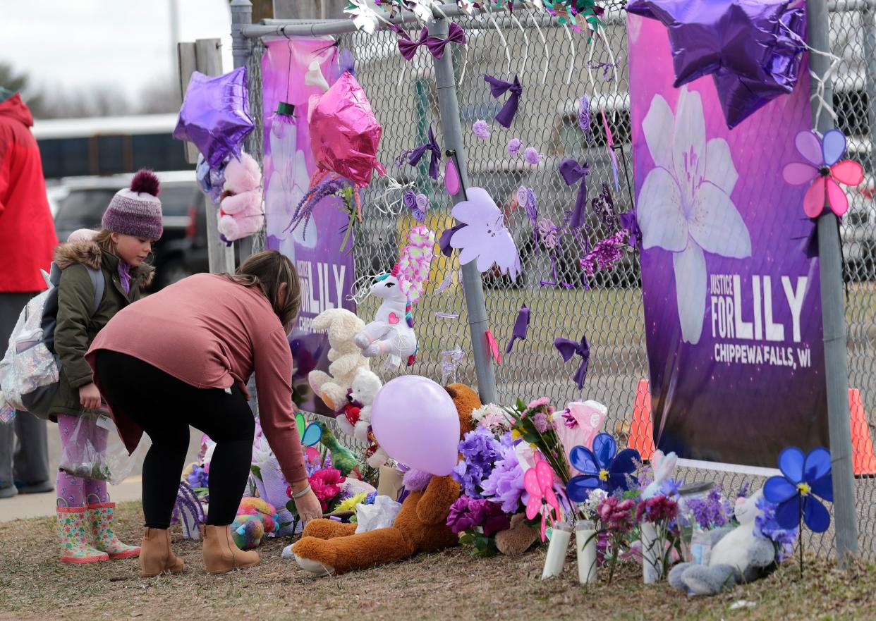 Tiffany Thompson and her step-daughter Lexy Frank, 8, leave a stuffed animal and drawing at a large memorial at Parkview Elementary School after the homicide of Iliana "Lily" Peters, 10, Tuesday, April 26, 2022, in Chippewa Falls, Wis.