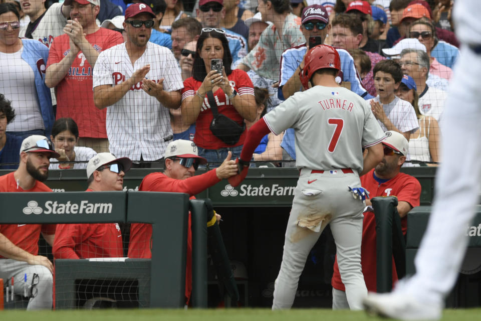 Philadelphia Phillies' Trea Turner (7) celebrates with manager Rob Thomson, third from left, at the dugout after scoring on a Brandon Marsh single during the first inning of a baseball game against the Chicago Cubs, Thursday, July 4, 2024, in Chicago. (AP Photo/Paul Beaty)