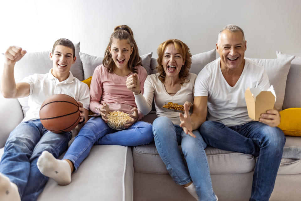 Excited, happy big family watching basketball match on the couch at home