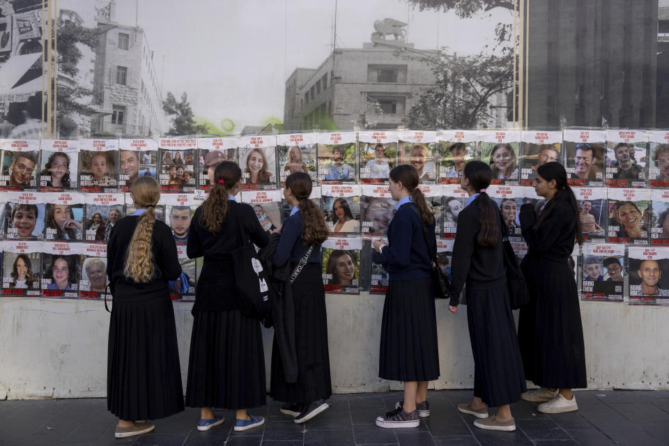 Women look at photos of Israelis missing and held captive in Gaza, in downtown Jerusalem, Sunday, Dec. 3, 2023. Hamas militants kidnapped about 240 people in an Oct. 7 attack and released over 100 of them during a weeklong cease-fire that ended on Friday. (AP Photo/Ohad Zwigenberg)