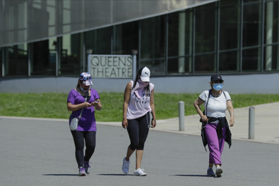 Women wear protective masks during the coronavirus pandemic as they pass the Queens Theatre, Tuesday, May 26, 2020, in the Queens borough of New York. (AP Photo/Frank Franklin II)