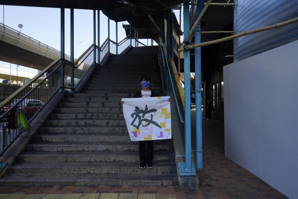 A pro-democracy activist holds banner with Chinese reads "Release", during a protest outside the Chinese central government's liaison office, in Hong Kong, Monday, Dec. 28, 2020, to demand the release of the 12 Hong Kong activists detained at sea by Chinese authorities. (AP Photo/Kin Cheung)