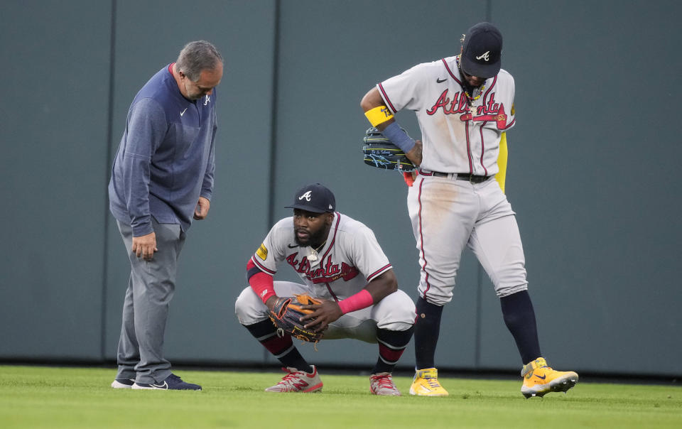 Atlanta Braves center fielder Michael Harris II, center, is checked by a trainer, left, and right fielder Ronald Acuna Jr., right, after Harris ran into the wall while trying to catch a triple by Colorado Rockies' Hunter Goodman during the second inning of a baseball game Tuesday, Aug. 29, 2023, in Denver. (AP Photo/David Zalubowski)
